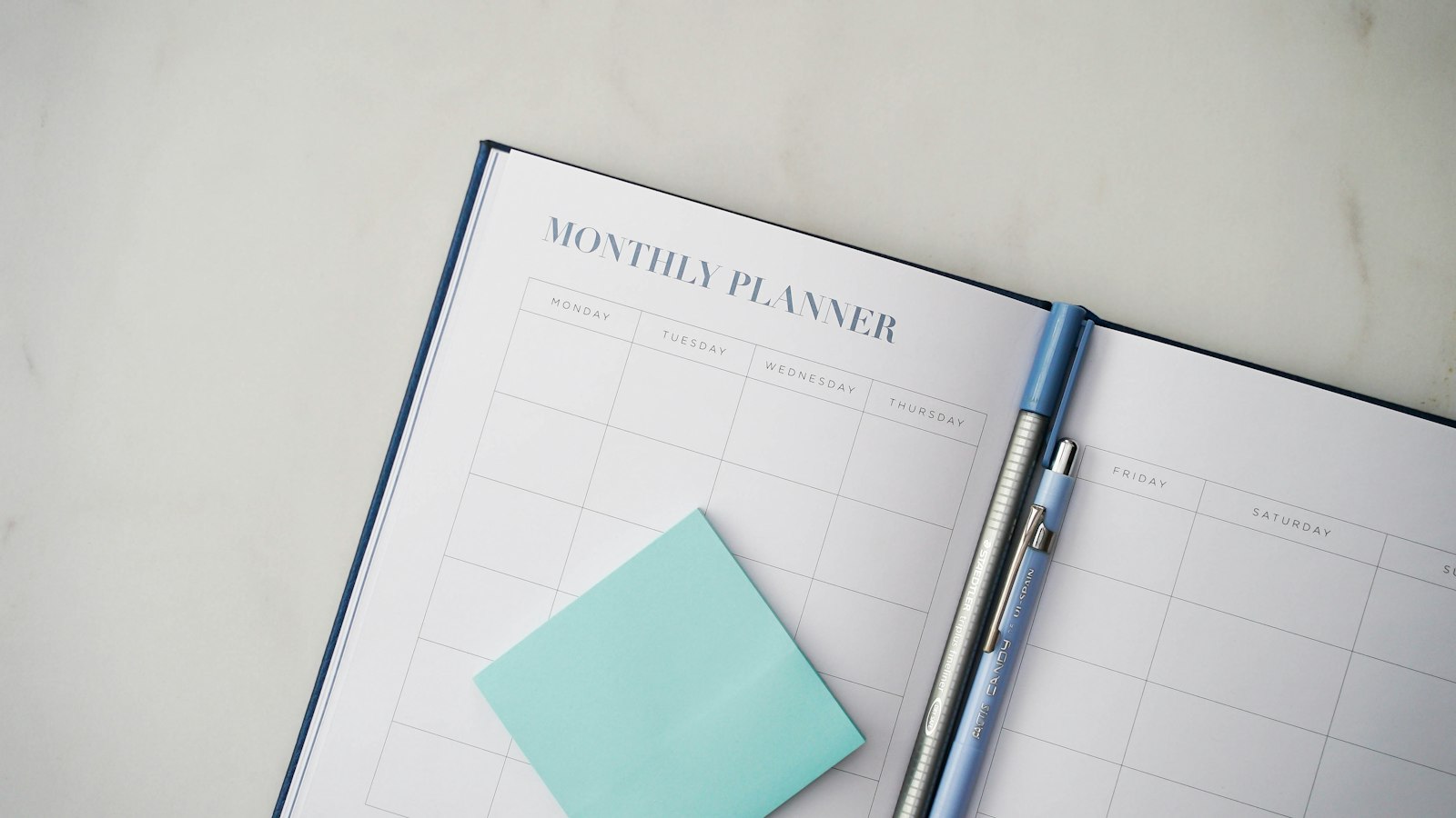 Open planner with a pen, used to chart symptoms across the menstrual cycle