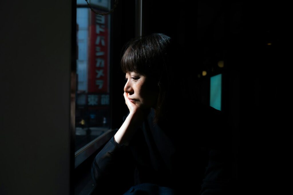 Woman looking out of a window at night, illustrating how long a person can go without sleep